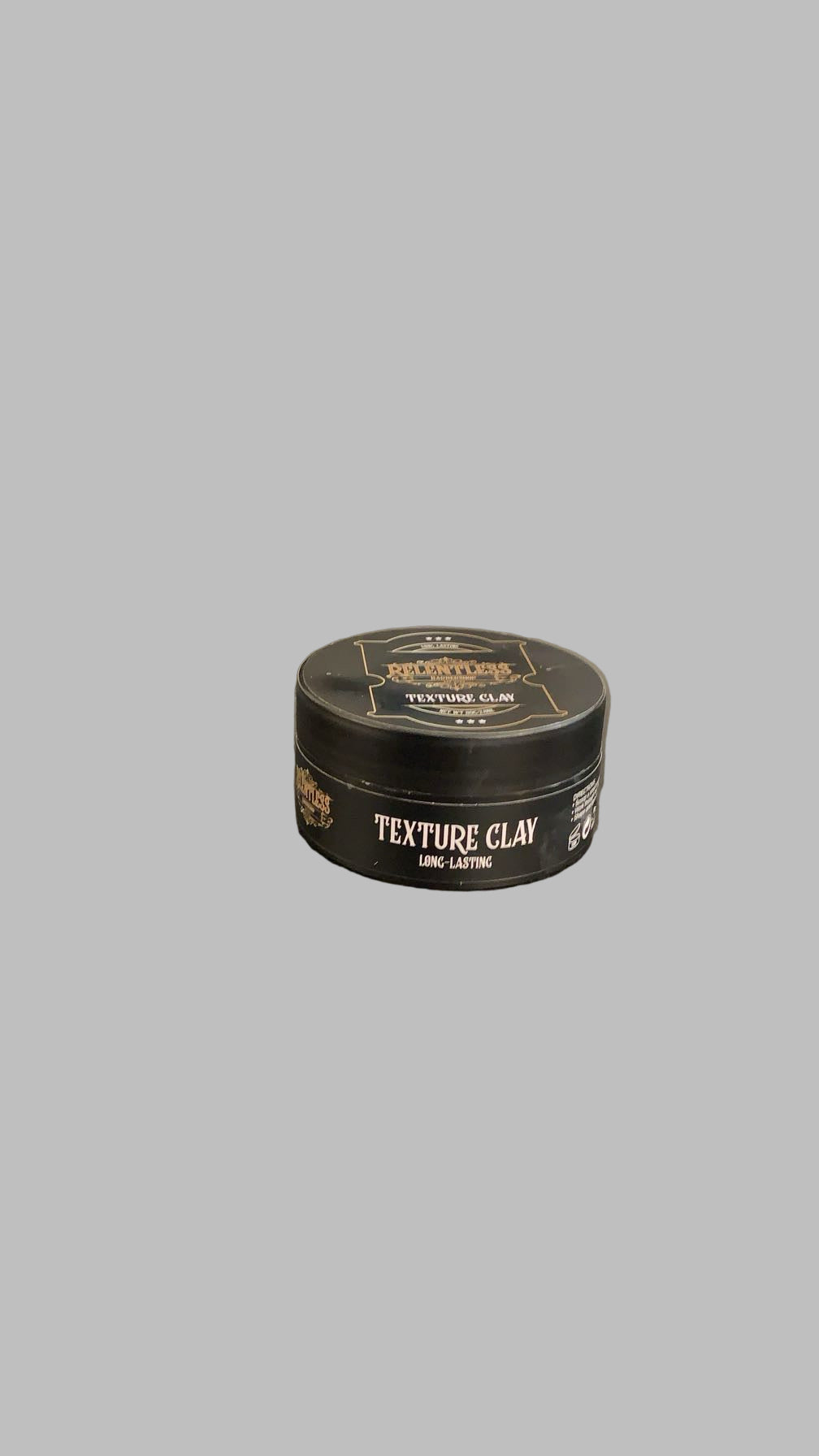 Black container of texture clay on a reflective surface