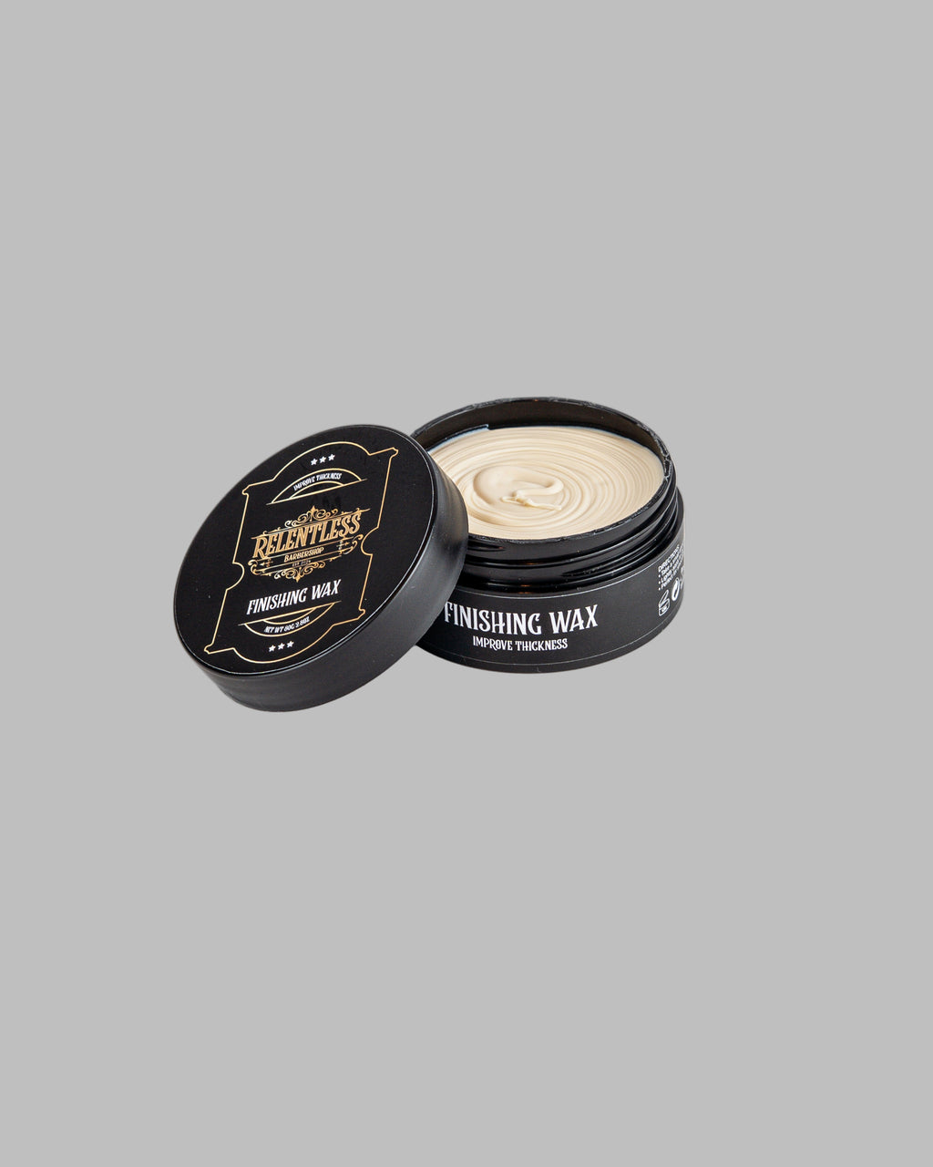 Black container of finishing wax with open lid on a white background